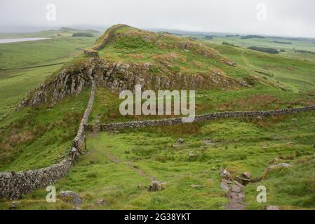 Vestiges du mur d'Hadrien, l'ancien mur-frontière romain traversant le nord de l'Angleterre, alors qu'ils serpentent à travers les collines à l'ouest du fort romain Housesteads. Longeant l'ensemble du site classé au patrimoine mondial de l'UNESCO, le chemin du mur d'Hadrien est l'un des sentiers de randonnée les plus populaires d'Angleterre. Banque D'Images