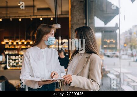 deux femmes d'affaires avec leur masque de visage discutant de points de vue différents travail Banque D'Images