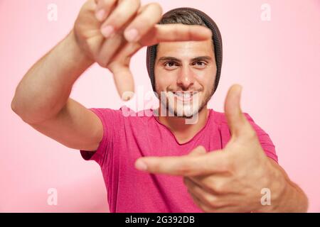 Créateur heureux positif homme bonne humeur porter chemise faire les doigts cadre isolé sur fond de couleur rose. Banque D'Images
