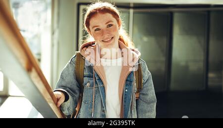 Bonne jeune femme à l'université. Une étudiante en vêtements décontractés souriant à l'appareil photo de l'université. Banque D'Images