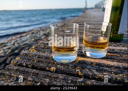 Boire un whisky écossais single malt au coucher du soleil avec vue sur la mer, l'océan ou la rivière, visites privées de la distillerie de whisky en Écosse, Royaume-Uni Banque D'Images