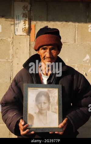 Zhang Zhengbi, 74 ans, avec une photo de sa femme birmane bien-aimée décédée il y a 8 ans. La mémoire quand ses parents et frères et sœurs ont été tués avant qu'il ne quitte Longling City à l'âge de 17 ans est encore vive dans son esprit. Il avait l'habitude d'essayer d'envoyer des lettres à son neveu, le seul parent qu'il a quitté, pendant des décennies jusqu'à ce qu'il réussisse. Néanmoins, les rêves de visiter son neveu et de construire des tombes pour les membres de sa famille ne seront peut-être jamais réalisés des maladies séniles et de sa vie pauvre. Chiang Rai, Thaïlande. 24 janvier 2009. Une partie de la photo, exilé Kuomintang de retour à la mère patrie, par Banque D'Images