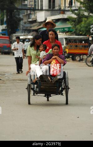 Depuis l'époque coloniale française, les «cyclos» ont existé pour transporter des passagers d'un endroit à l'autre. Le cyclo cambodgien est un pousse-pousse à vélo, un véhicule à 3 roues qui transporte les passagers en amont entre les roues avant avec le conducteur de vélo derrière et au-dessus de ses passagers. Le siège passager est très confortable, mais une seule personne peut s'asseoir, bien que si tout le monde s'assoit sur les genoux, plus de passagers peuvent être emmenés. Phnom Penh, Cambodge. 19 juin 2006. Banque D'Images