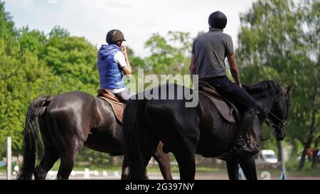 Jeune homme et fille cavalier marron et noir cheval dans le sport équestre compétition.Equitation sur l'arène.dressage test.compétitions équestres, équestrian Banque D'Images