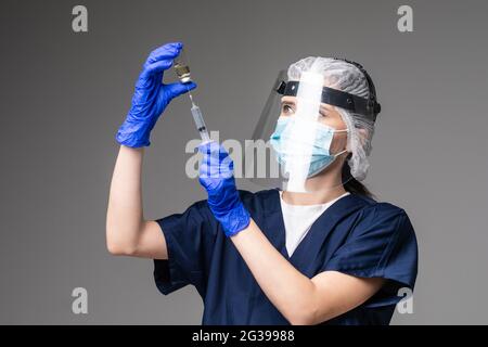 Photo de beau médecin examen de l'hôpital préparer la dose de seringue patient vaccin traitement par injection porter masque manteau facial plastique bouclier chirurgical Banque D'Images