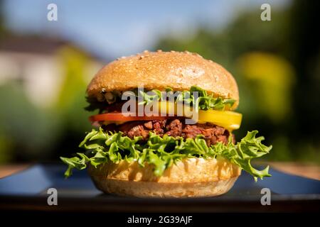Hamburger végétarien aux haricots verts sur une assiette noire à l'extérieur Banque D'Images