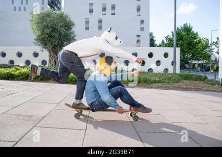 Deux hommes avec masque animal sur la longue planche dans le parc Banque D'Images