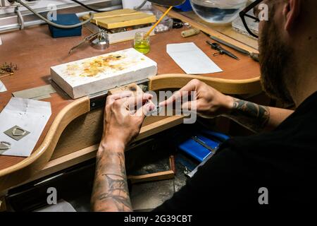 Les mains des hommes dans l'atelier de bijoux de classement d'un morceau d'argent. Plan de détail Banque D'Images