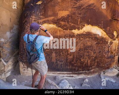 Man Photographs Rochester Creek Petroglyph Panel près d'Emery, Utah. Banque D'Images