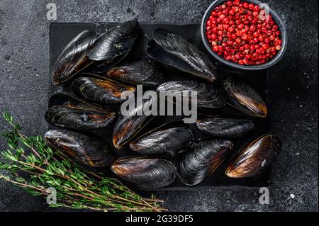 Moules cuites dans des coquilles sur un plateau en marbre. Arrière-plan noir. Vue de dessus Banque D'Images