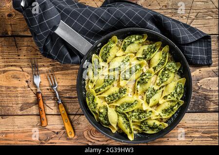 Pâtes Jumbo Shell Conchiglioni farcies aux épinards et au fromage cuits avec de la sauce dans une casserole. Arrière-plan en bois. Vue de dessus Banque D'Images