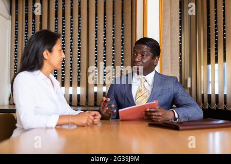 L'homme d'affaires et la femme d'affaires communiquent et signent des documents à la table de négociation au bureau Banque D'Images