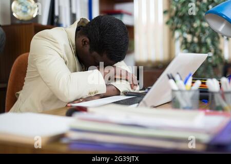 Employé de bureau américain africain fatigué dormant à table Banque D'Images