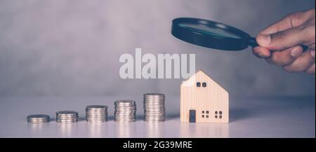 Mains de l'homme d'affaires tenant loupe modèle de maison avec la recherche de biens immobiliers et d'investissement immobilier pour le profit, la planification de résidentiel et d'incom Banque D'Images