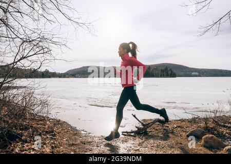 Entraînement de fille de course de printemps en dehors de jogging au bord du lac dans la nature campagne. Femme athlète coureur d'entraînement cardio Banque D'Images