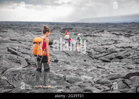 Groupe de randonneurs marchant sur le volcan Hawaï champ de lave randonnée aventure Happy Woman avec sac à dos à Big Island, Hawaï. Touristes marchant sur guidé Banque D'Images