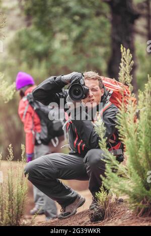 Photographe homme prenant des photos avec un appareil photo professionnel des animaux de la nature. Randonneurs randonnée sur voyage aventure dans la forêt en utilisant l'équipement à Banque D'Images