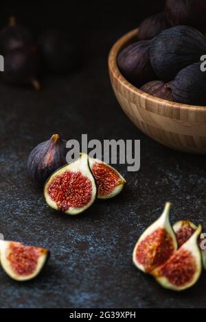 Figues en tranches sur la table et fruits mûrs dans un bol en bois Banque D'Images