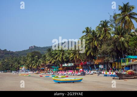 Des bateaux de pêche colorés et des cabanes de plage le long de la plage sous les palmiers et le ciel bleu, Palolem, Goa, Inde Banque D'Images