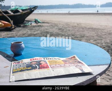 Copie du journal Goa Times couché sur une table au soleil sur la plage de Palolem, Goa, Inde Banque D'Images