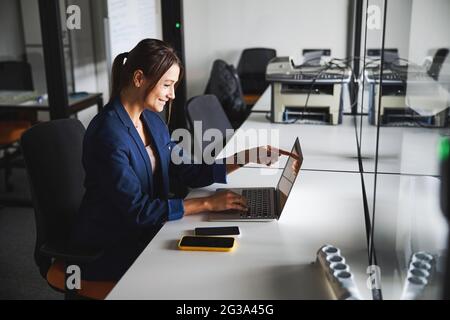 Beau web designer élégant travaillant à l'ordinateur portable tout en utilisant Internet dans l'espace de travail Banque D'Images