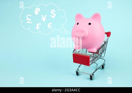 Porggy Bank Inside Panier avec hologramme numérique hologramme monde devises dans le nuage pensé au-dessus de sa tête sur fond bleu. Le concept de SAV Banque D'Images