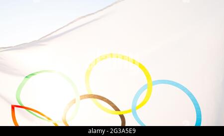 Le drapeau olympique flotte dans le vent contre le fond du ciel et le soleil en gros plan. Le symbole des Jeux Olympiques de Sports, fans de come Banque D'Images