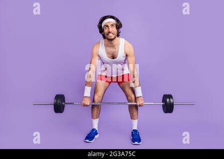 Photo pleine grandeur de jeune homme fou dans les lunettes look copyspace essayant de soulever la barbell de soulèvement isolé sur fond violet de couleur Banque D'Images