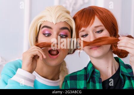 Deux amies gaies jouent avec des cheveux et de la grimace. Les filles caucasiennes posent drôle pour les portraits de gros plan de l'appareil photo Banque D'Images