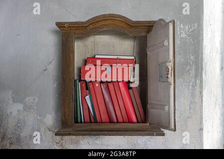 La littérature religieuse dans l'ancienne bibliothèque accrochée sur le mur dans la sacristie de l'église. Banque D'Images