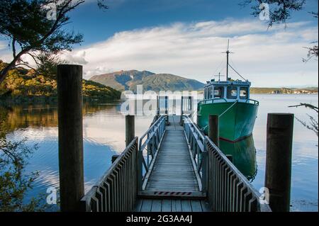 Rotorua, Nouvelle-Zélande - juillet 2018 : Rotomahana. Lac Crater, Waimangu , Rotorua, Nouvelle-Zélande. Jetée en bois, bateau vert, scène tranquille Banque D'Images