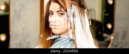 Portrait d'une belle jeune femme caucasienne qui obtient de la feuille sur ses cheveux avant de teindre dans un salon de beauté Banque D'Images