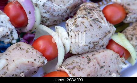 Brochettes de porc crues aux épices, tomates cerises et oignons sur des brochettes prêtes à cuire. Kebab frais et cru Banque D'Images