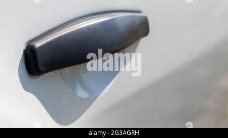 Poignée de porte en plastique noir d'une voiture blanche moderne. Transport. Détail et partie de la voiture. Poignée d'ouverture de porte de l'extérieur Banque D'Images