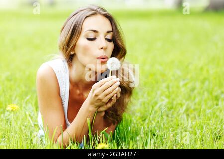 Belle jeune femme avec le pissenlit lying on grass Banque D'Images