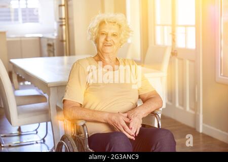 Femme âgée souriante en fauteuil roulant après un accident vasculaire cérébral dans une maison de retraite Banque D'Images