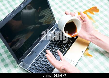 Carnet avec un café versé dans une tasse. Accident informatique. Ordinateur portable détruit avec du liquide. Café renversé sur le clavier de l'ordinateur portable. Renverser du café Banque D'Images