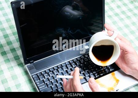 Carnet avec un café versé dans une tasse. Accident informatique. Ordinateur portable détruit avec du liquide. Café renversé sur le clavier de l'ordinateur portable. Renverser du café Banque D'Images