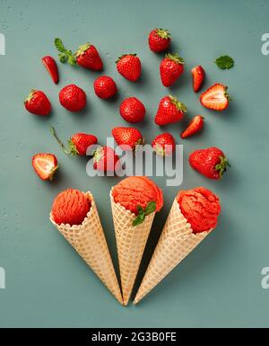 Glace fraîche à la fraise dans des cônes avec des fraises sur fond bleu. Vue de dessus de la glace italienne. Concept de crème glacée Banque D'Images