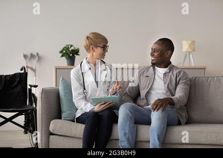 Médecin vérifiant le patient, le service à domicile et les soins de santé. Bonne femme d'âge moyen médecin et adulte afro-américain appréciant de bons résultats, s'assoit sur s. Banque D'Images