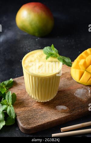 Lassi de mangue indienne ou smoothies de fruits sur fond noir. Mélanger à la mangue. Lassi de fraîcheur fait de yaourt, eau, épices, fruits et glace. Banque D'Images