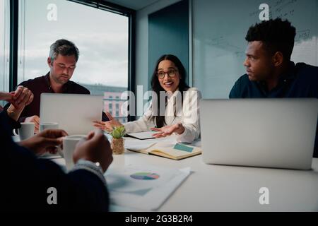 Jeune femme d'affaires en discussion avec ses collègues masculins dans un bureau moderne Banque D'Images