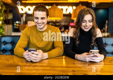 Phubbing, toujours connecté, la dépendance à internet, young couple in cafe à à leurs smartphones, social network concept Banque D'Images