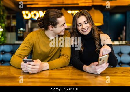 Phubbing, toujours connecté, la dépendance à internet, young couple in cafe à à leurs smartphones, social network concept Banque D'Images