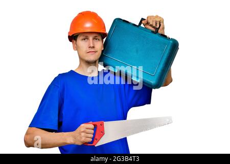 Portrait d'un jeune constructeur sur un fond clair. Un ouvrier dans un casque de construction tient une scie à métaux et une valise avec des outils dans ses mains. Mise en page Banque D'Images