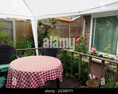 Une petite surface de terrasse dans un jardin à l'arrière couvert d'un belvédère blanc et montrant une table Banque D'Images