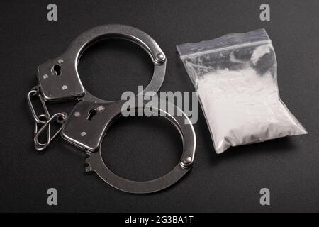 vue de dessus de la répression contre la drogue, des menottes et de la poudre de cocaïne blanche. Banque D'Images
