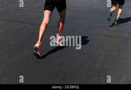 jambes deux coureurs mâles courent marathon sur asphalte foncé Banque D'Images
