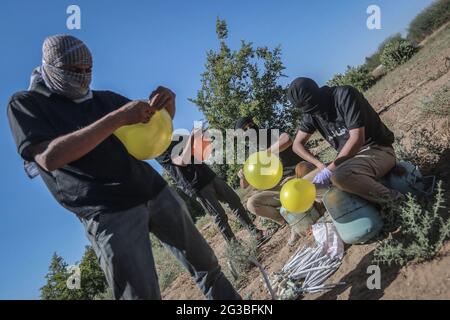 Gaza, Territoires palestiniens. 15 juin 2021. Les Palestiniens masqués se préparent à libérer des ballons remplis de gaz réfrigérant, fixés à des dispositifs incendiaires et à des matières inflammables, qui seront propulsés par le vent dans le territoire israélien, à partir d'une zone située à l'est de la ville de Gaza. Israël se vante mardi d'une marche controversée du drapeau à travers Jérusalem, avec la crainte d'une nouvelle flambée de violence, alors que quelque 5,000 nationalistes de droite doivent défiler à travers la vieille ville de Jérusalem en brandant le drapeau bleu et blanc d'Israël. Credit: Mohammed Talatene/dpa/Alay Live News Banque D'Images