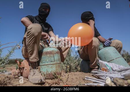 Gaza, Territoires palestiniens. 15 juin 2021. Les Palestiniens masqués se préparent à libérer des ballons remplis de gaz réfrigérant, fixés à des dispositifs incendiaires et à des matières inflammables, qui seront propulsés par le vent dans le territoire israélien, à partir d'une zone située à l'est de la ville de Gaza. Israël se vante mardi d'une marche controversée du drapeau à travers Jérusalem, avec la crainte d'une nouvelle flambée de violence, alors que quelque 5,000 nationalistes de droite doivent défiler à travers la vieille ville de Jérusalem en brandant le drapeau bleu et blanc d'Israël. Credit: Mohammed Talatene/dpa/Alay Live News Banque D'Images